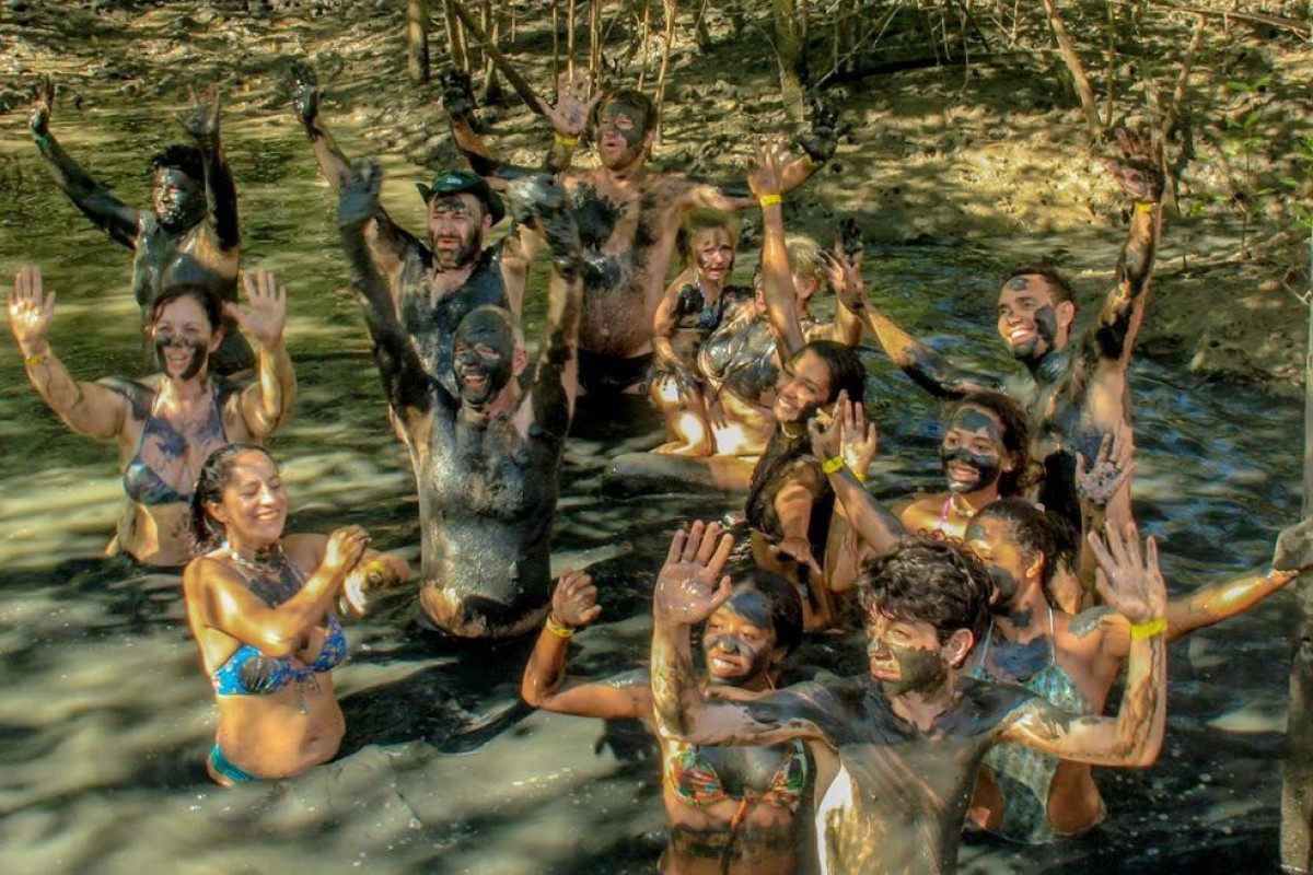 Grupo se divertindo no banho de argila do manguezal em Cabrália