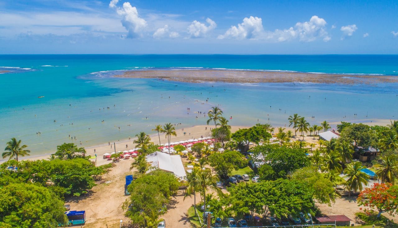 Vista aérea de praia com recifes e piscinas naturais em Porto Seguro