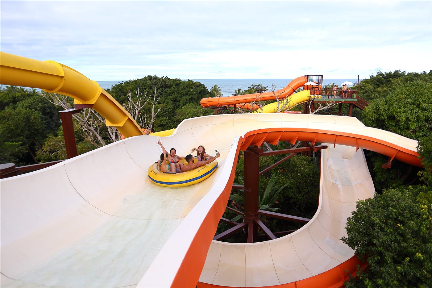 Família descendo toboágua no parque aquático em meio à mata