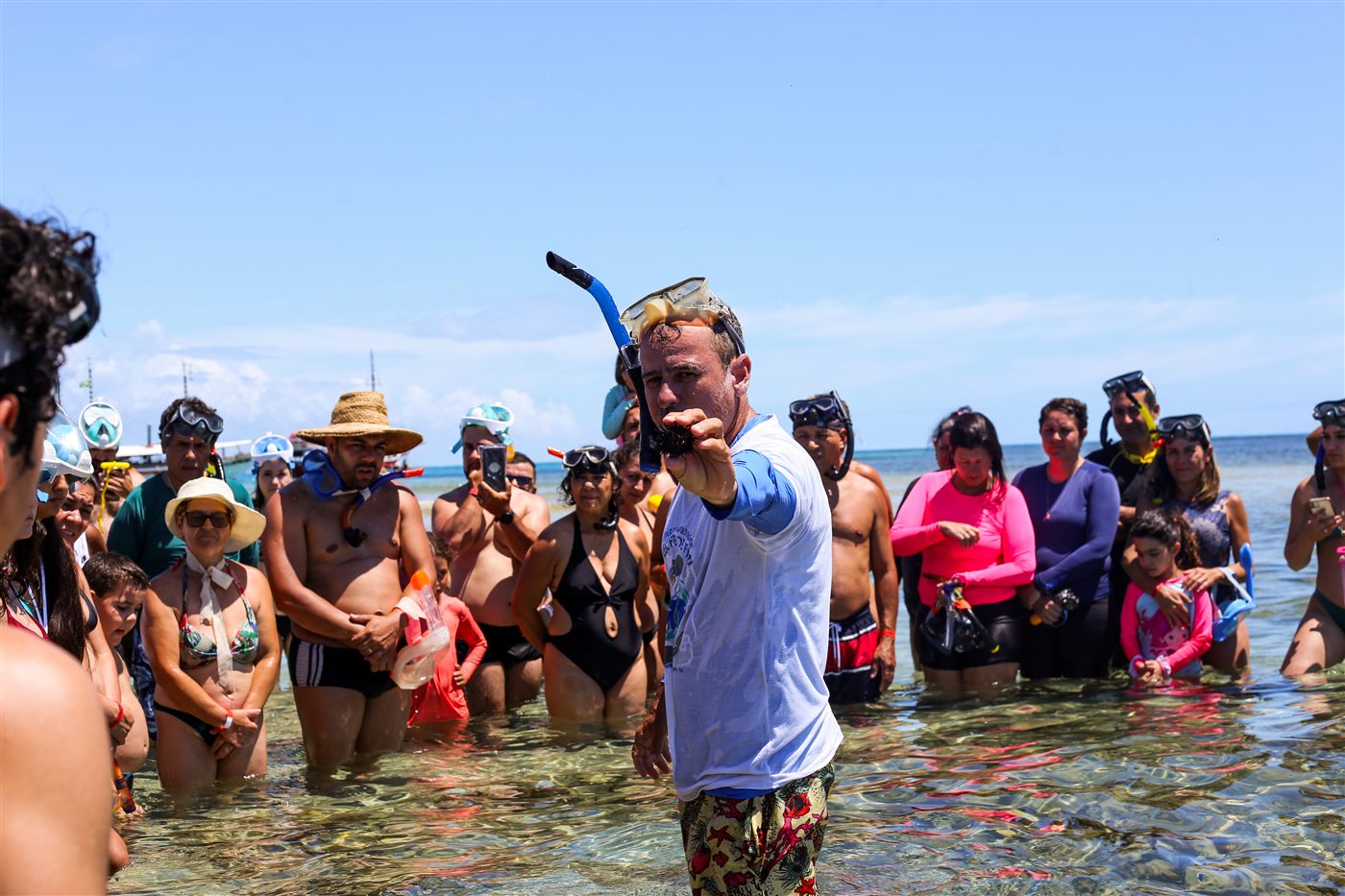 Guia orientando grupo de visitantes com snorkel na água