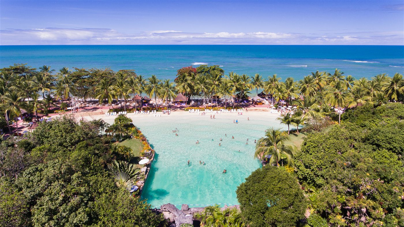 Vista aérea da piscina do Eco Parque entre coqueiros com o mar ao fundo