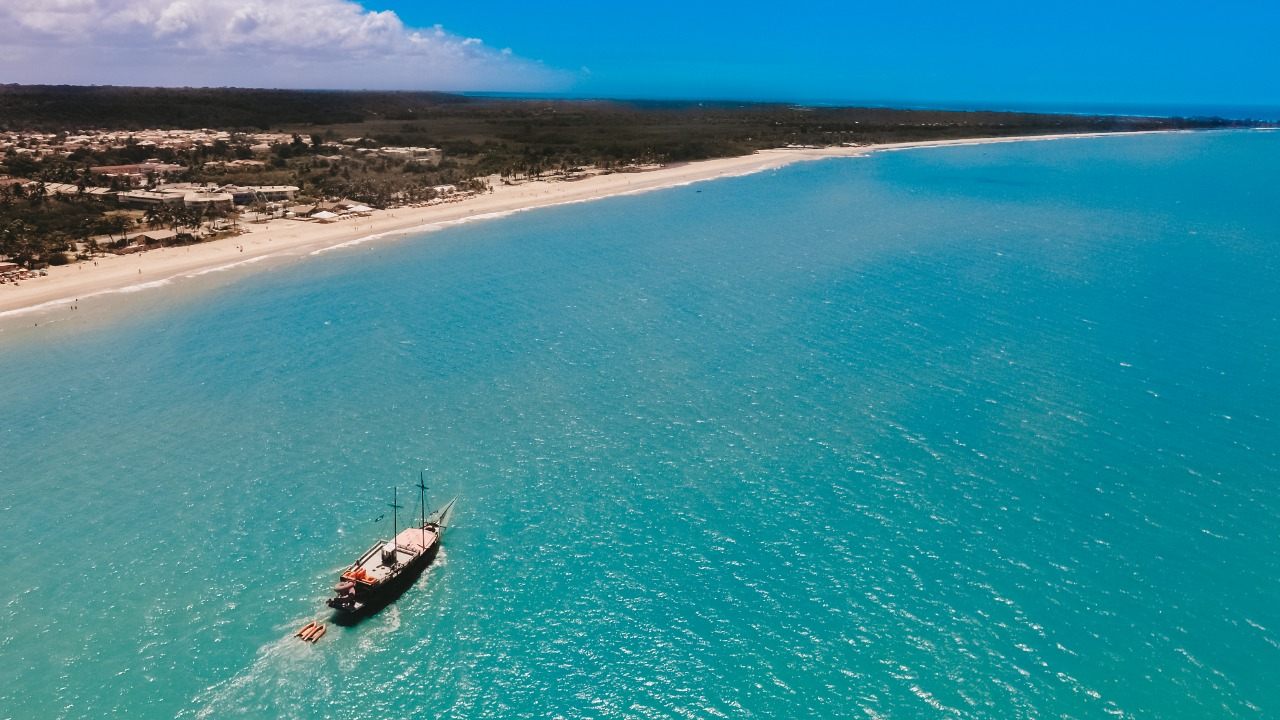 Vista aérea da escuna navegando no mar turquesa da orla de Porto Seguro