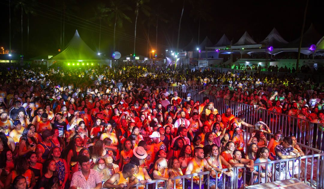 Festa noturna com tendas e público animado em Porto Seguro