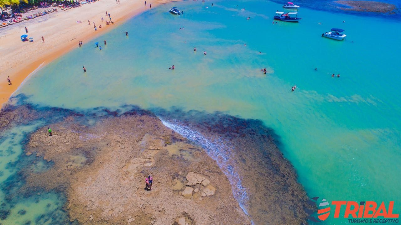 Vista aérea da praia de Taperapuã com recifes e mar turquesa